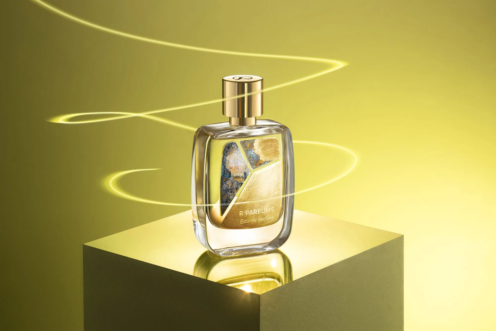 Eau de Hajime in the Patina bottle, standing on a lit block against a yellow ground, a ribbon of light curling around it