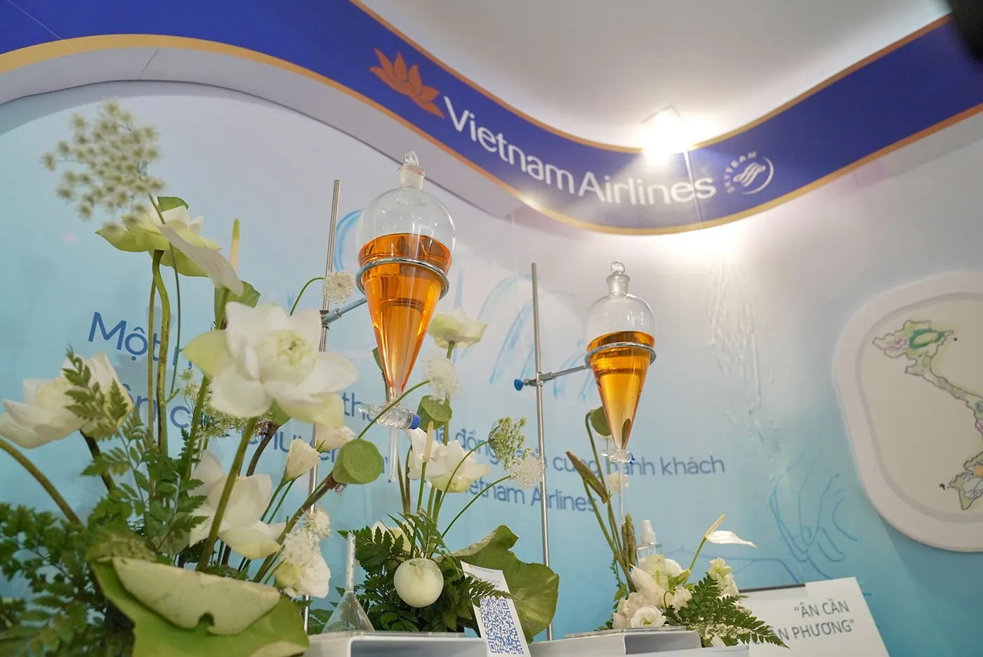 Vietnam Airlines display: glass funnels of amber oil among white lotus flowers