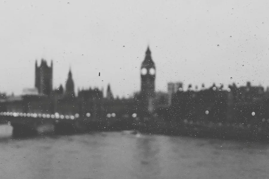 Ảnh đen trắng qua ô kính đọng mưa: tháp đồng hồ Big Ben và bờ sông London nhòe trong sương