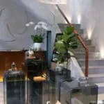 縮圖：R Parfums 展間裡的玻璃展示櫃、綠色盆栽與木扶手樓梯。