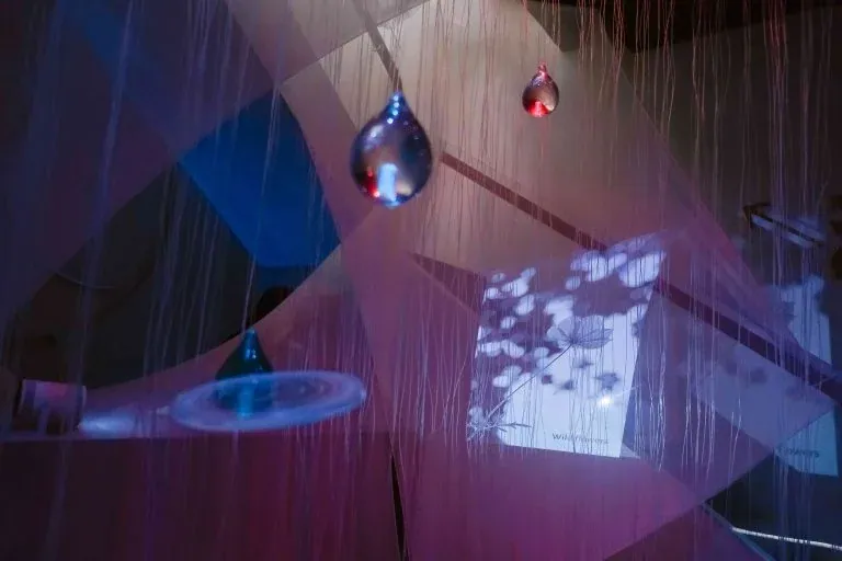 Pluviophile 嗅覺展期間，玻璃水滴懸在細線之間，籠在藍紫色的光裡。