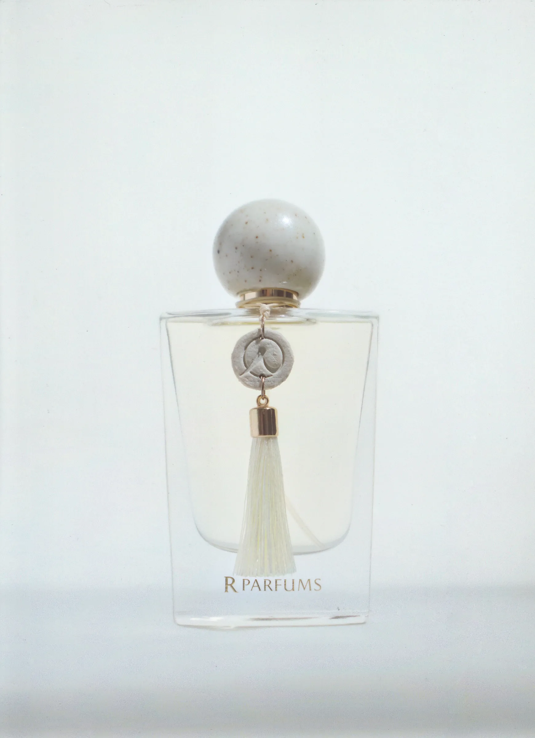 A Ceramic bottle with an ivory glazed cap and a white tassel