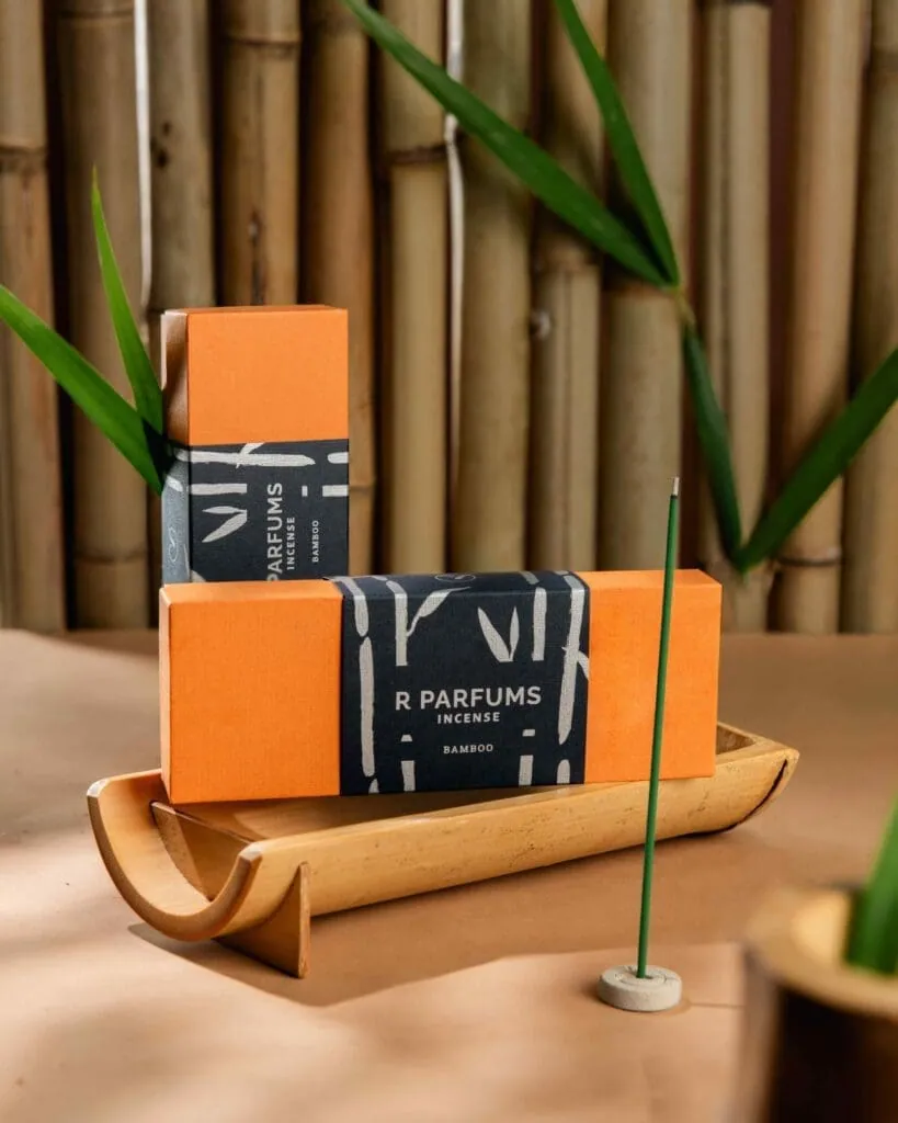 兩盒橘色的 R Parfums Incense Bamboo 放在竹管排成的托盤上，旁邊是一支綠色線香。