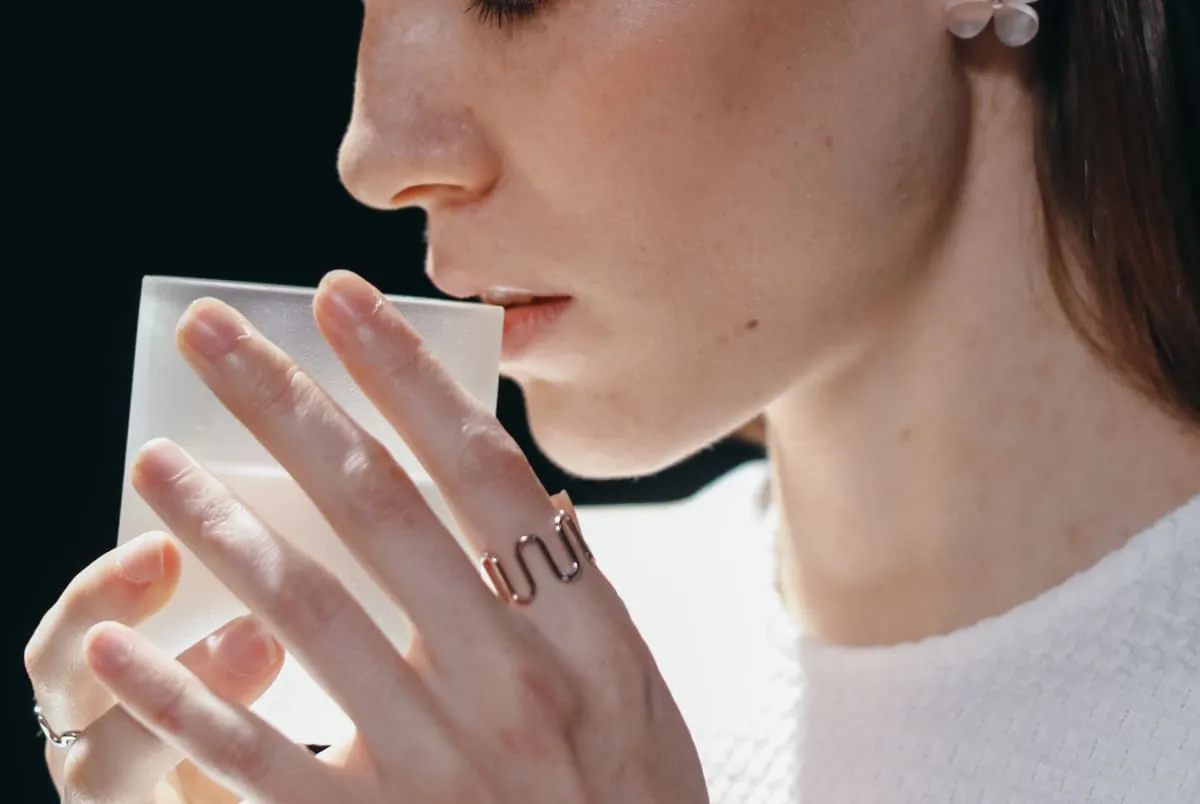 Gros plan sur une femme qui, les yeux fermés, boit dans une tasse en verre dépoli, comme si elle goûtait un souvenir