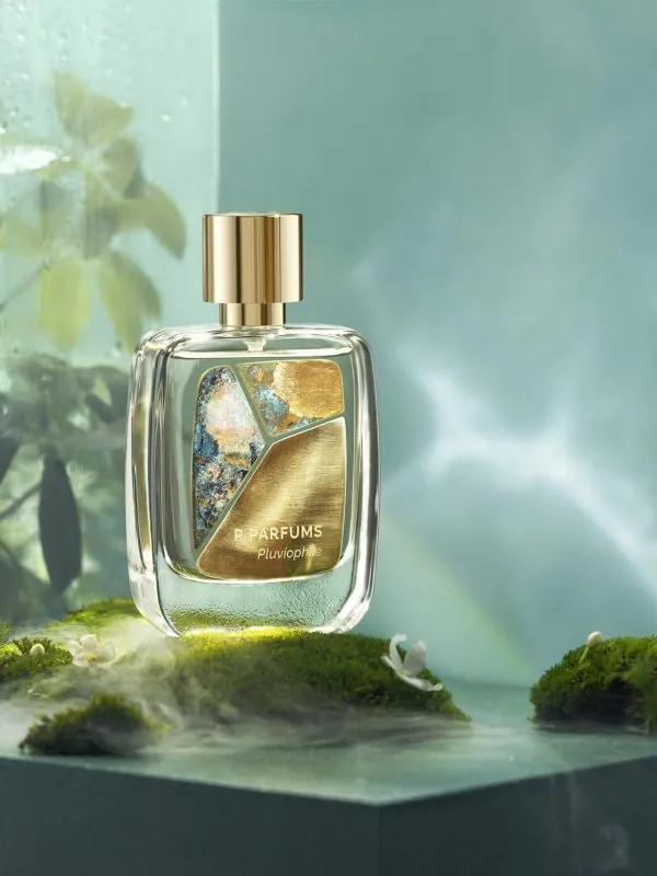 R Parfums Pluviophile 병, 젖은 이끼 위, 빗방울 맺힌 유리 너머 옅은 안개와 초록 잎