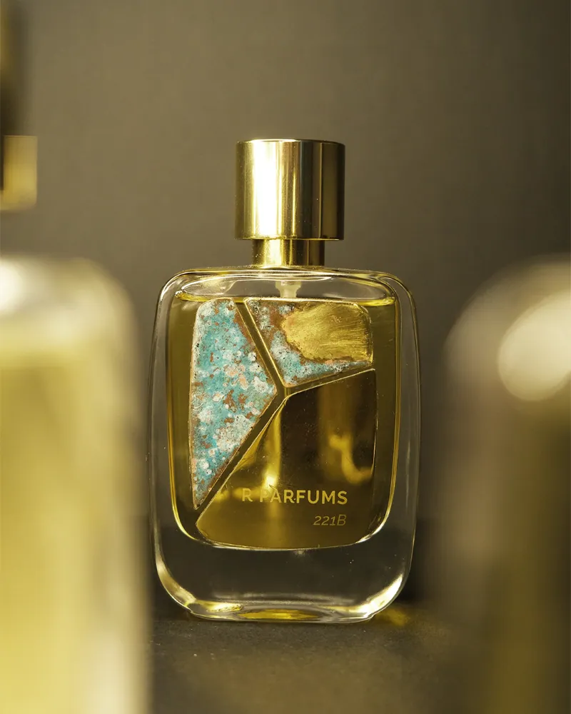 R Parfums 221B bottle with a pale blue-green patina brass plate brushed with gold, polished gold cap