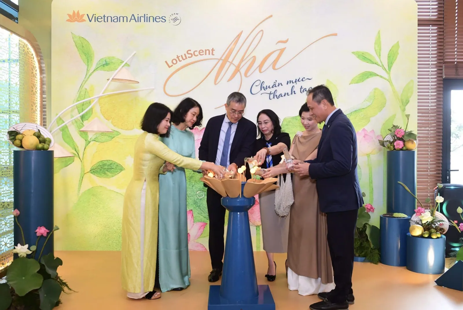 Lancement de « Nhã » : six personnes versent ensemble le parfum dans un socle en forme de lotus, devant un fond LotuScent Vietnam Airlines