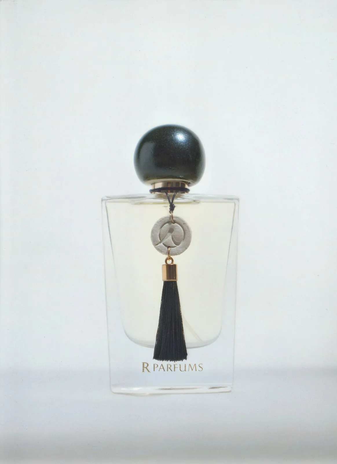 Ceramic bottle with a black-glazed cap, black tassel and a ceramic charm engraved with an R
