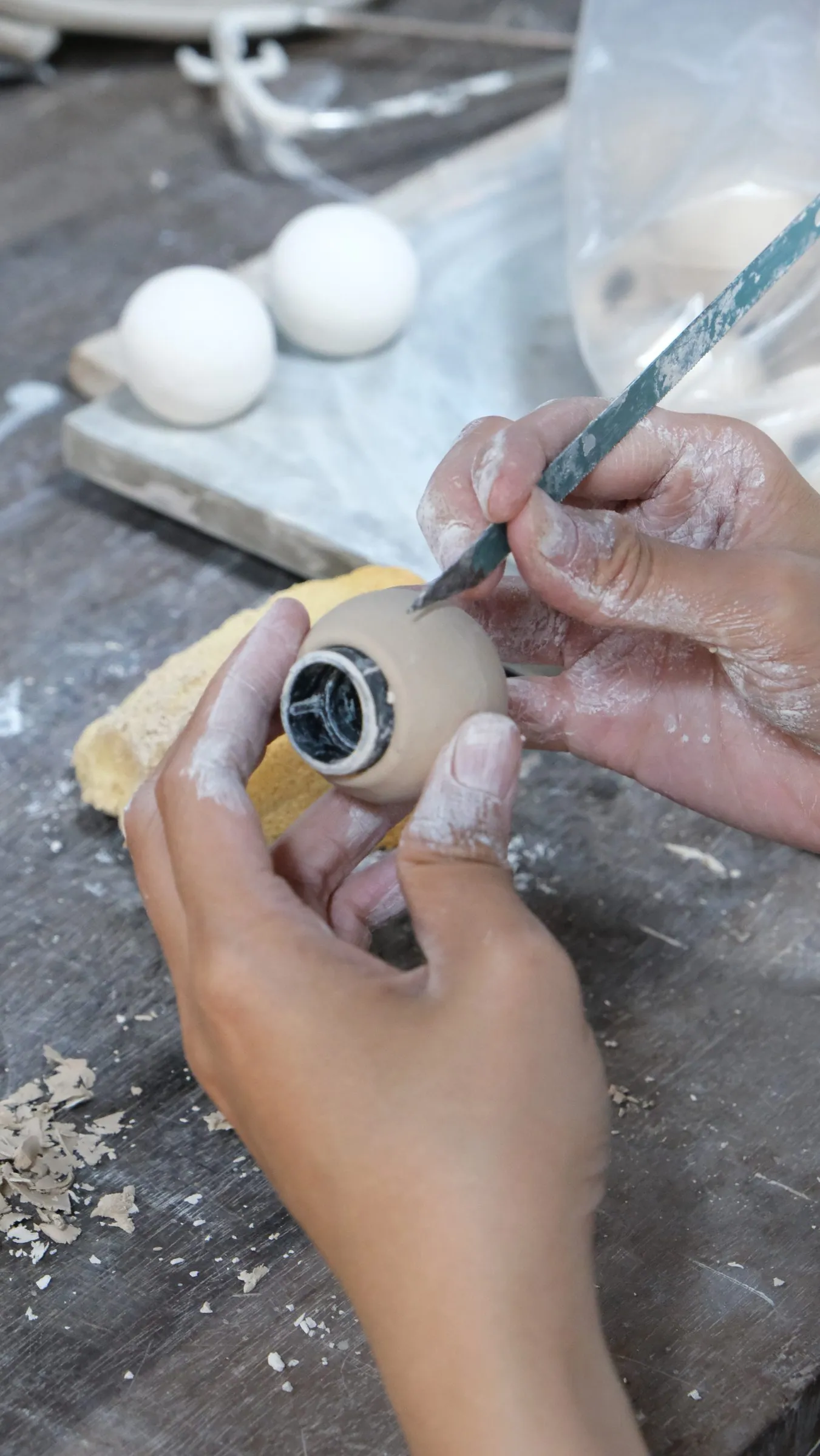 A sphere in close-up with a ring of black-and-white pattern at its mouth, a carving tool beside it