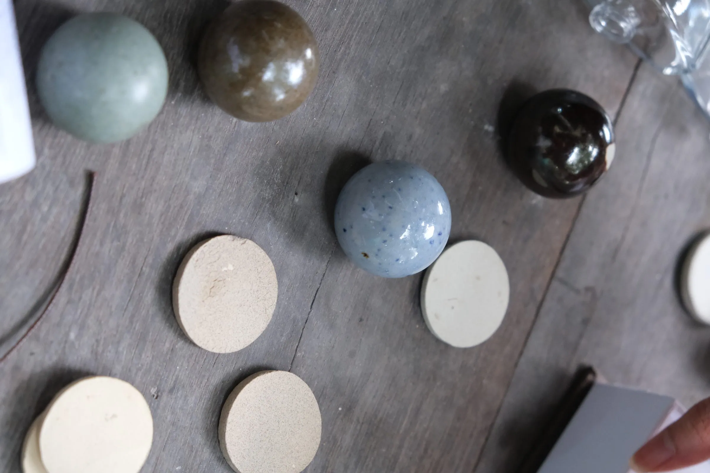 Fired ceramic spheres in blue-grey, brown, glossy black and speckled blue, with cream ceramic discs, on dark wood