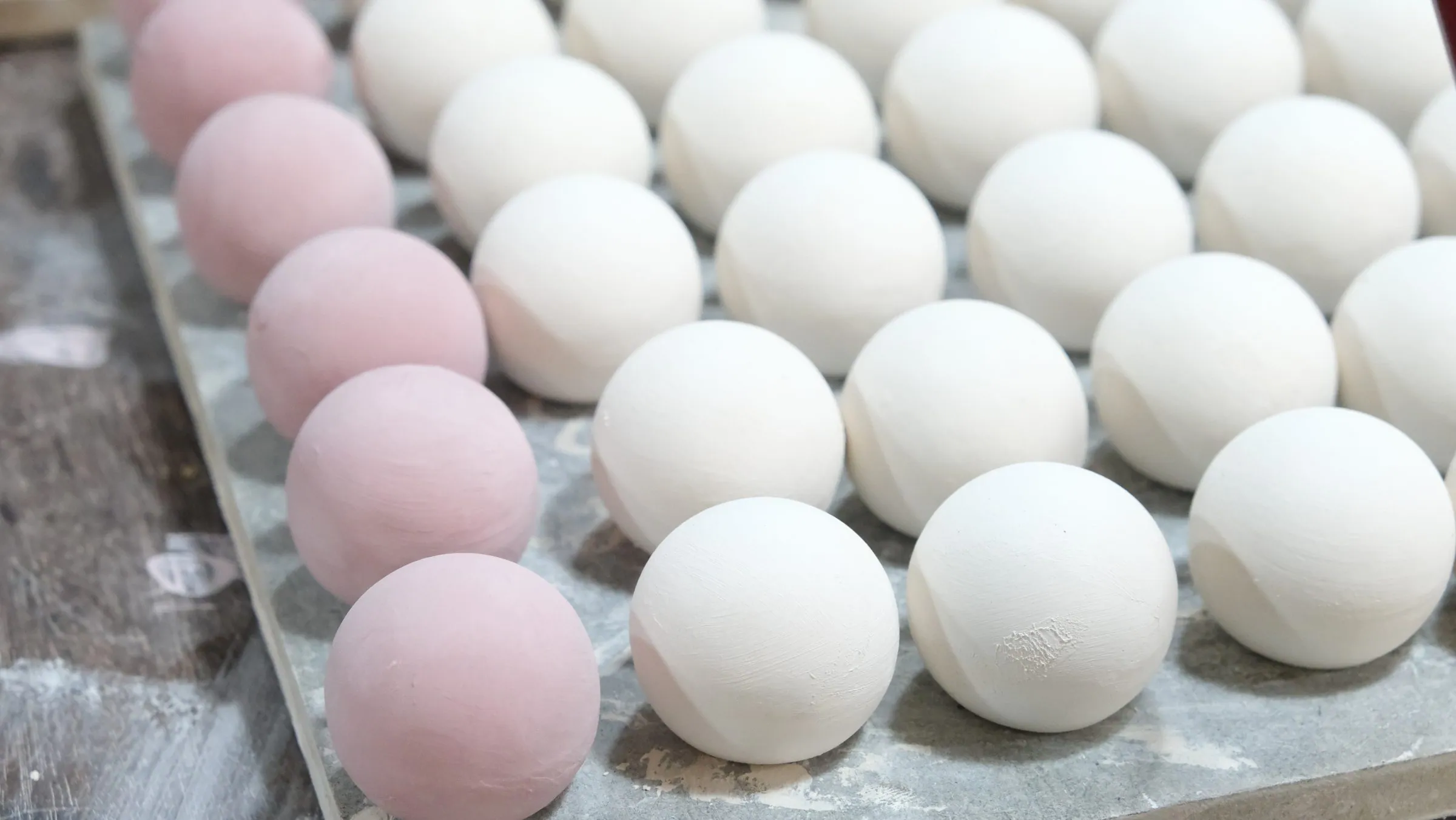 A board of spheres: the left-hand row glazed pink, the rest still white