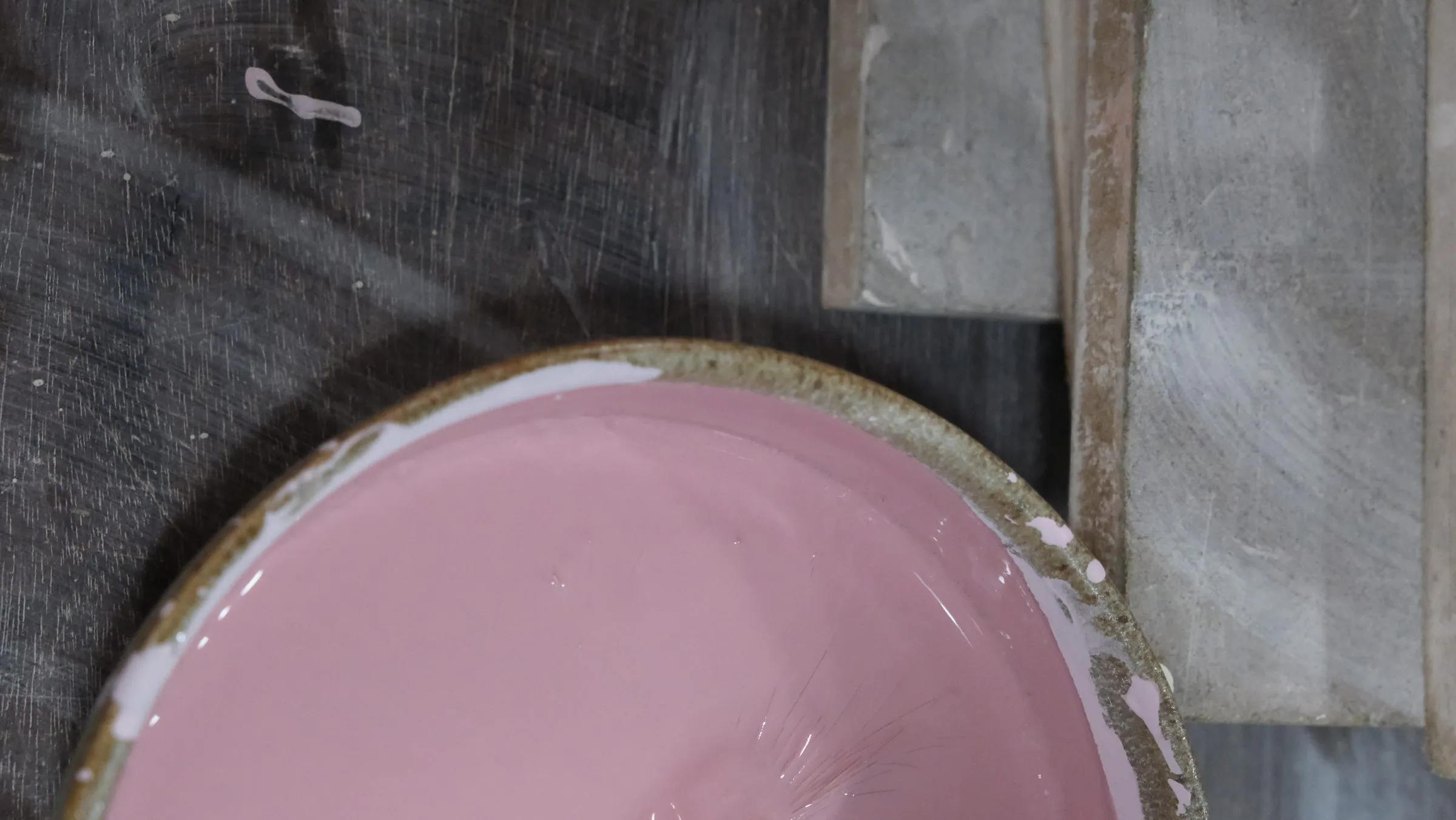 A bowl of thick pink raw glaze seen from above, on dark wood