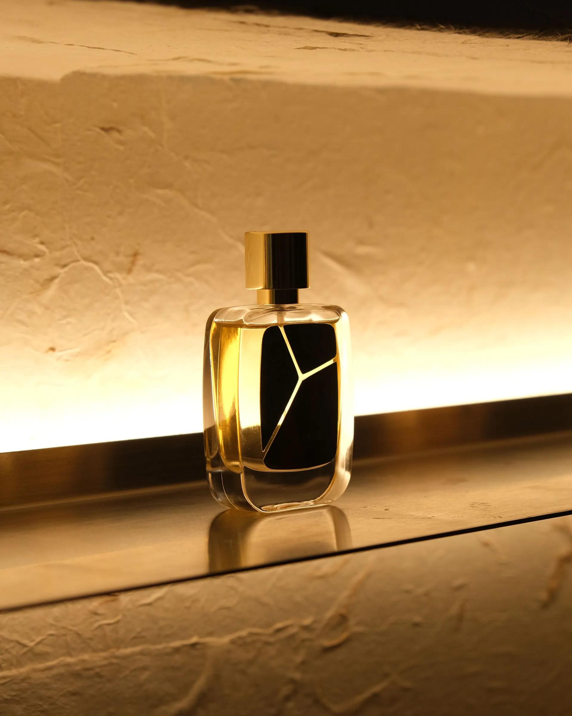 点亮的壁龛层架上,逆光中的 R Parfums 香水瓶