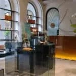 缩略图：R Parfums 展间的陈列区，有玻璃拱窗、摆着香水瓶的层架与暖光玻璃柜。