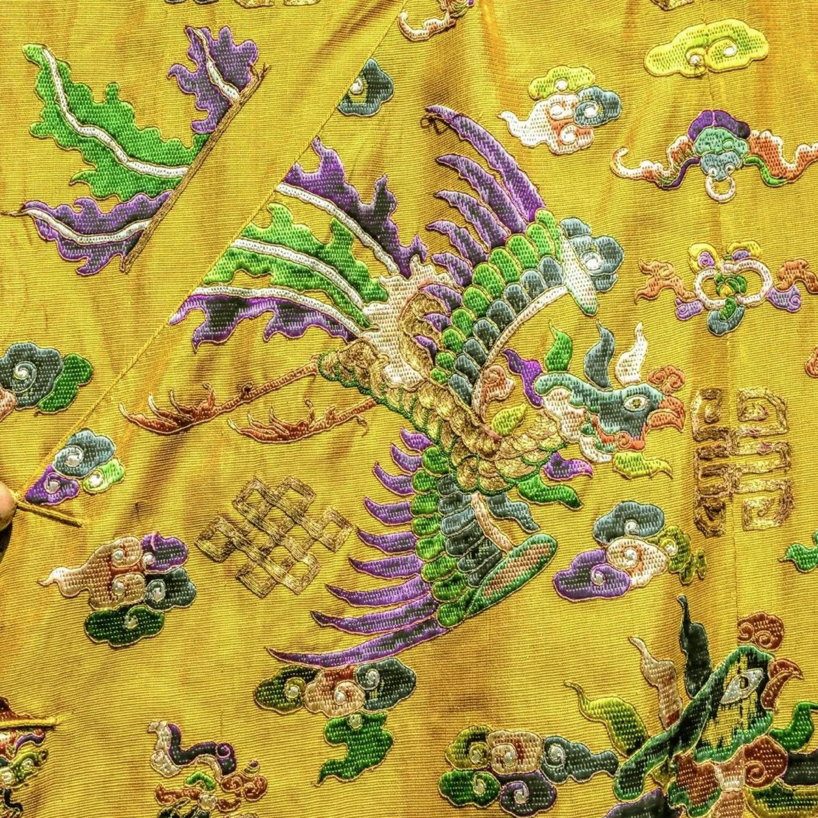 黄色丝绸特写,绣有凤凰与五彩祥云——传统服饰的纹样。