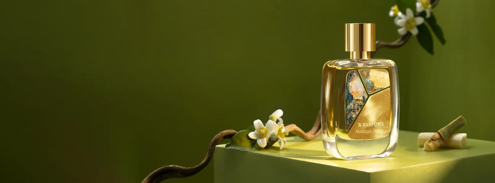 R Parfums 的 Nostalgic March 香水瓶，瓶身带 Patina 黄铜片，旁有柚子花枝与甘蔗段，衬着苔绿背景。