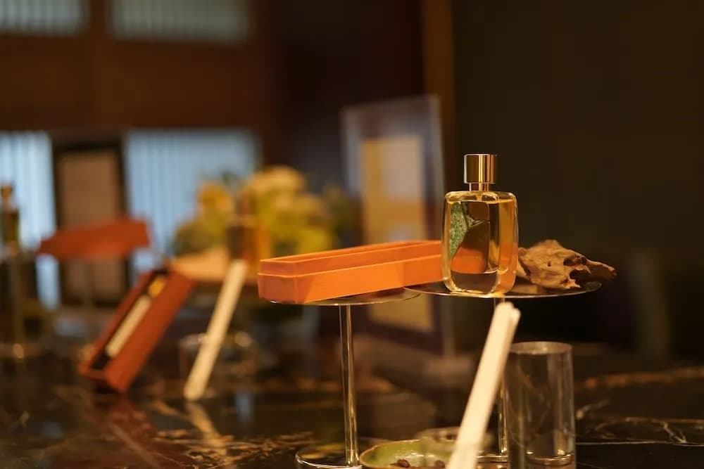 Oku 餐厅活动桌上的 R Parfums 香水瓶,瓶身镶着泛出铜绿的黄铜片,一旁是橘色试香纸盒与一块木头。