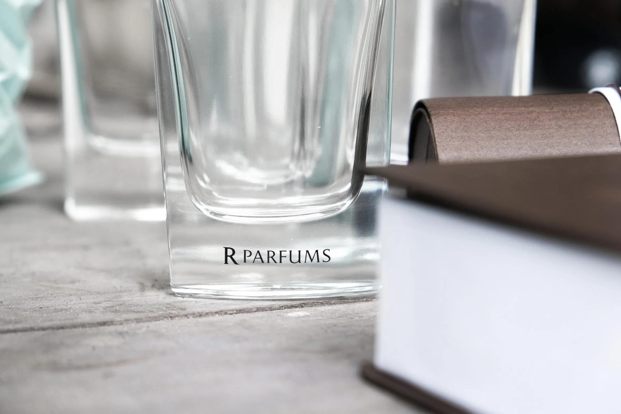 刻有 R PARFUMS 的方形玻璃瓶，旁边是棕色盒子。