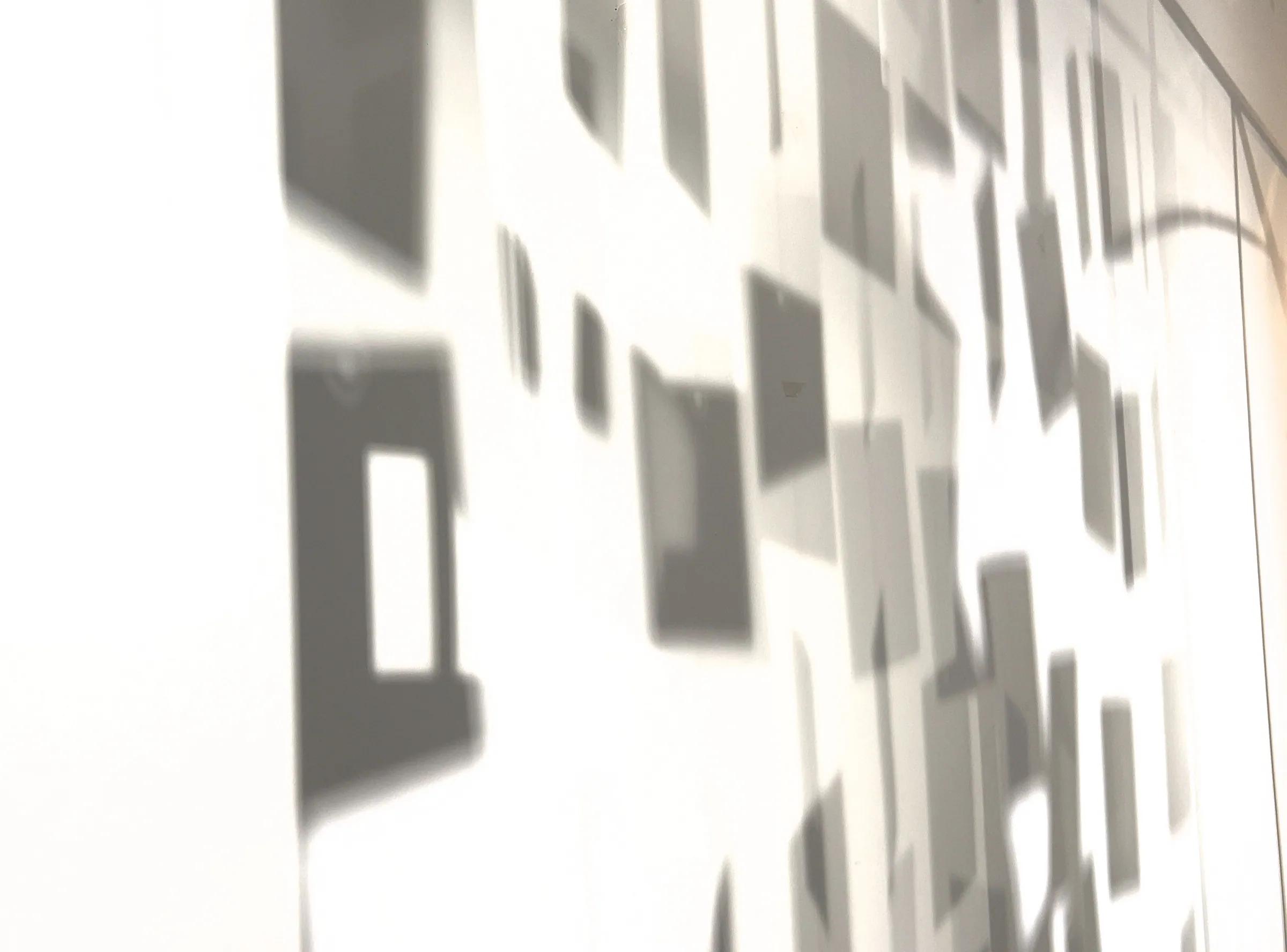 Shadows of hanging letter pages cast on a white wall