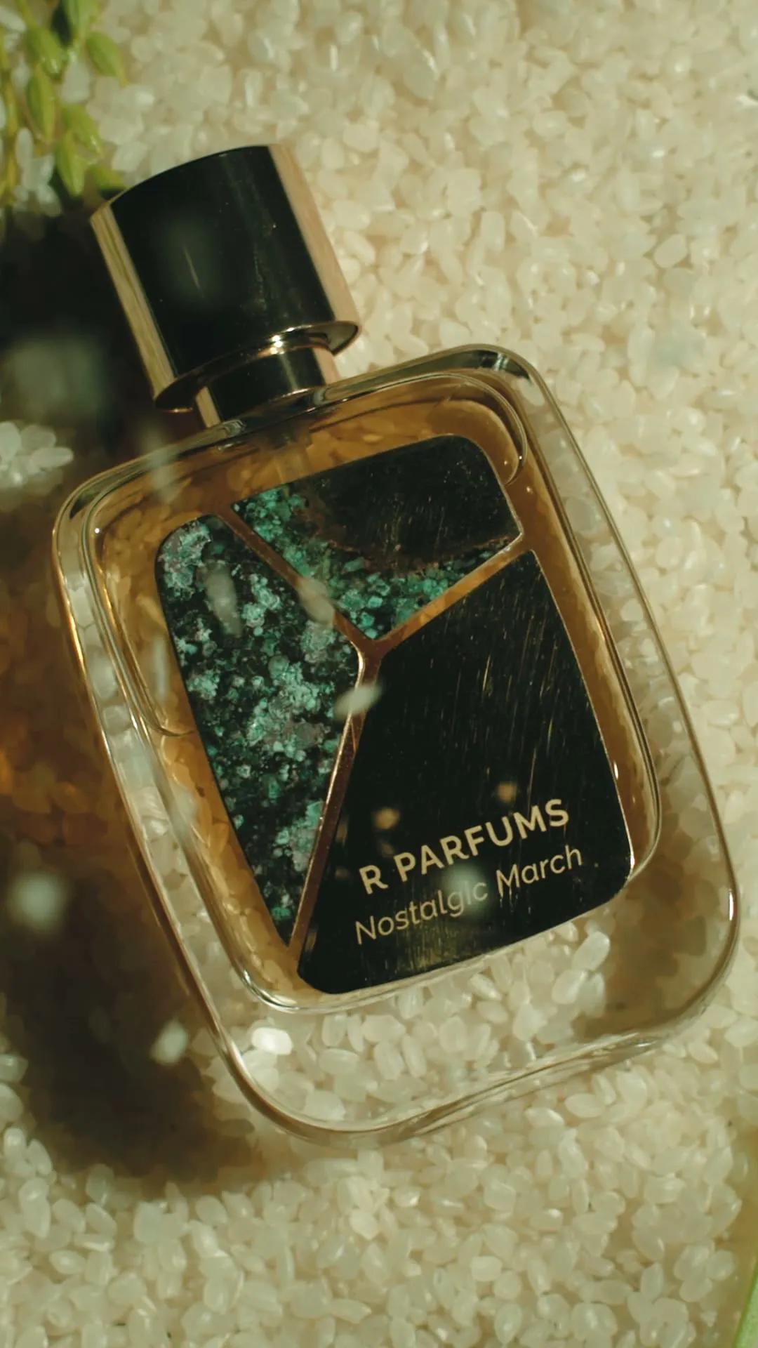 Khung hình từ phim năm 2022: chai Patina Nostalgic March nằm trong gạo trắng, dòng chữ “R PARFUMS Nostalgic March” trên mảnh đồng thau