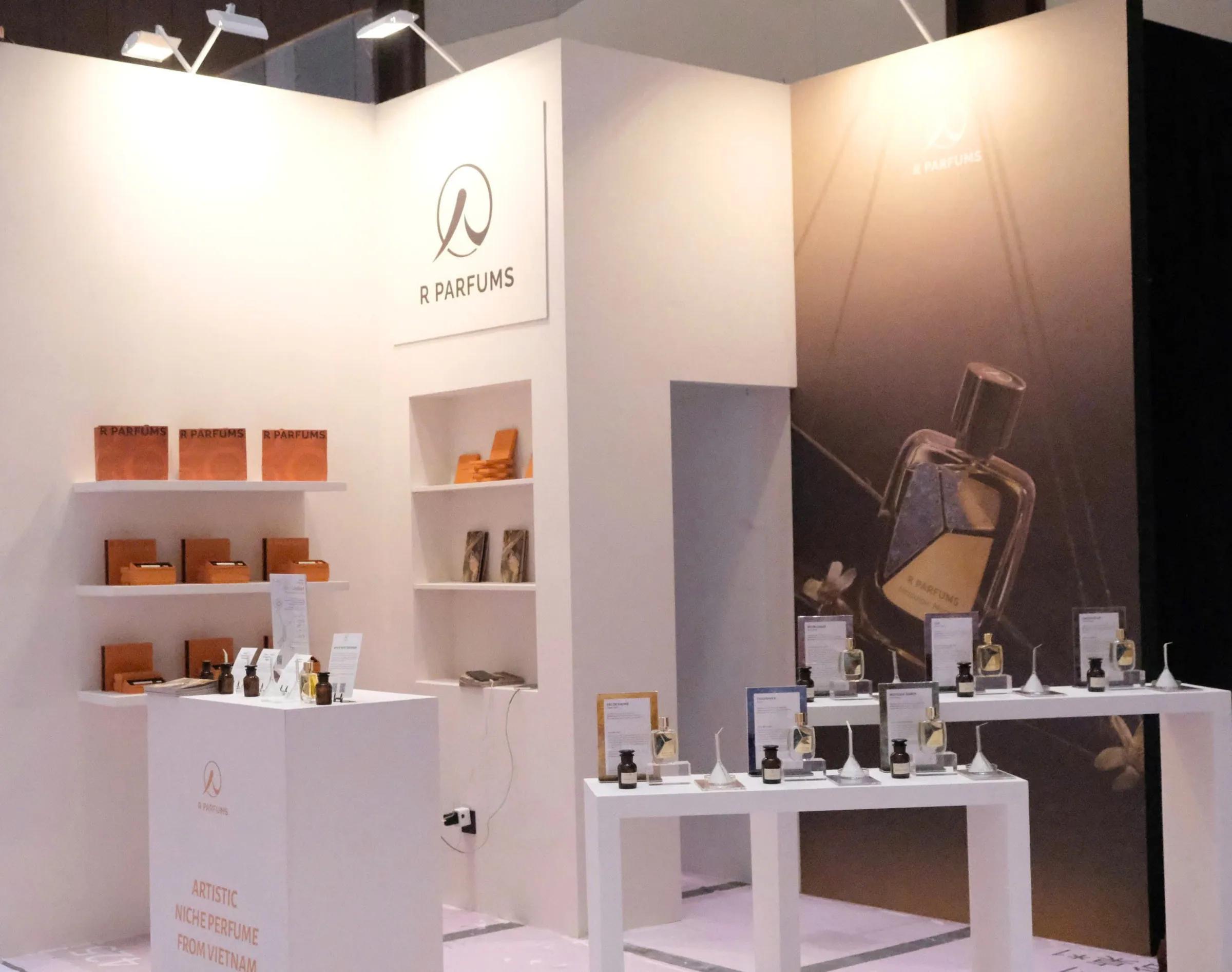R Parfums 在 Notes Shanghai 的 H11 展位：白墙、橘色礼盒，以及摆着 Patina 瓶的试香桌。