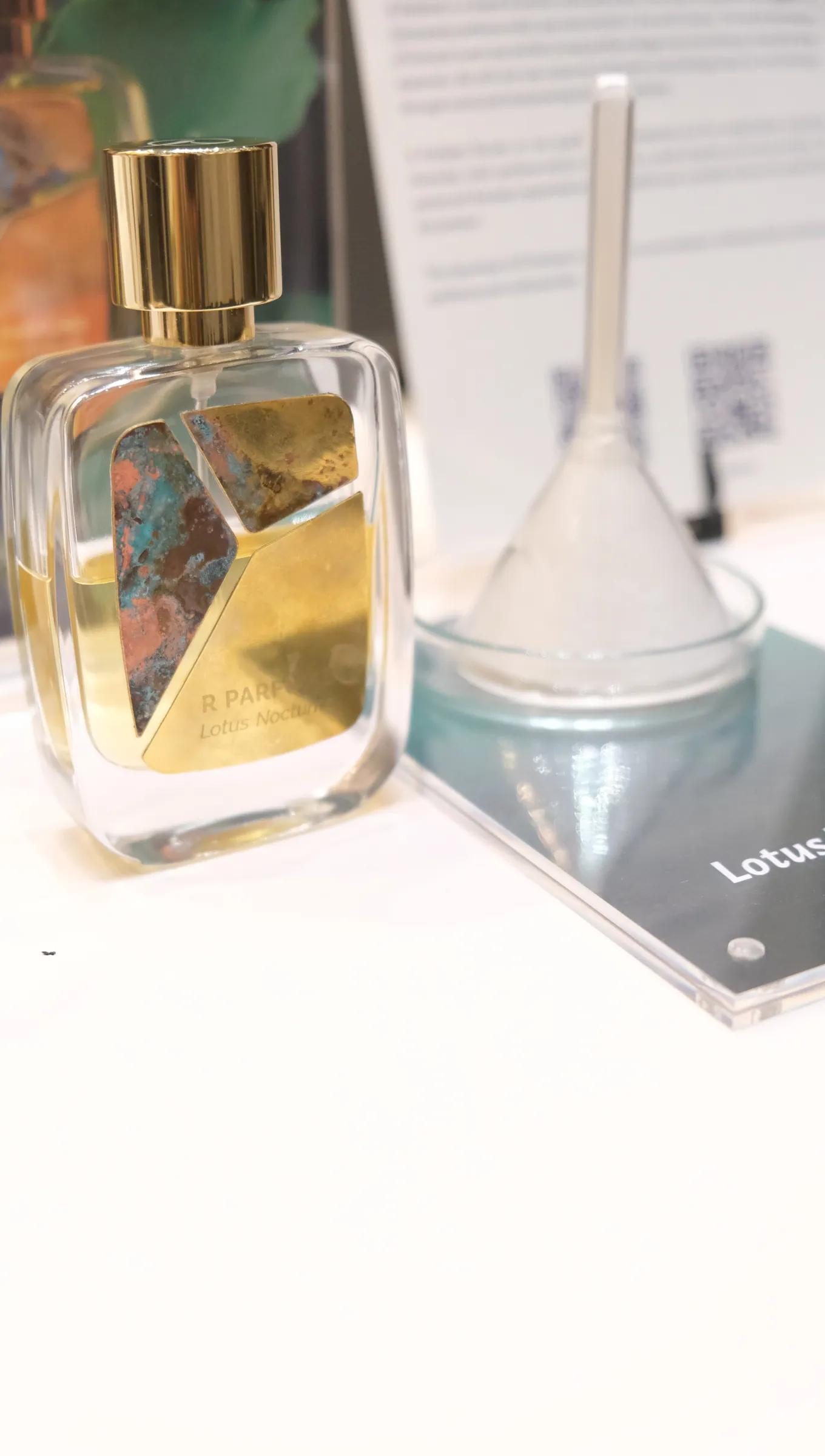 玻璃漏斗旁的 Lotus Nocturne 香水瓶。