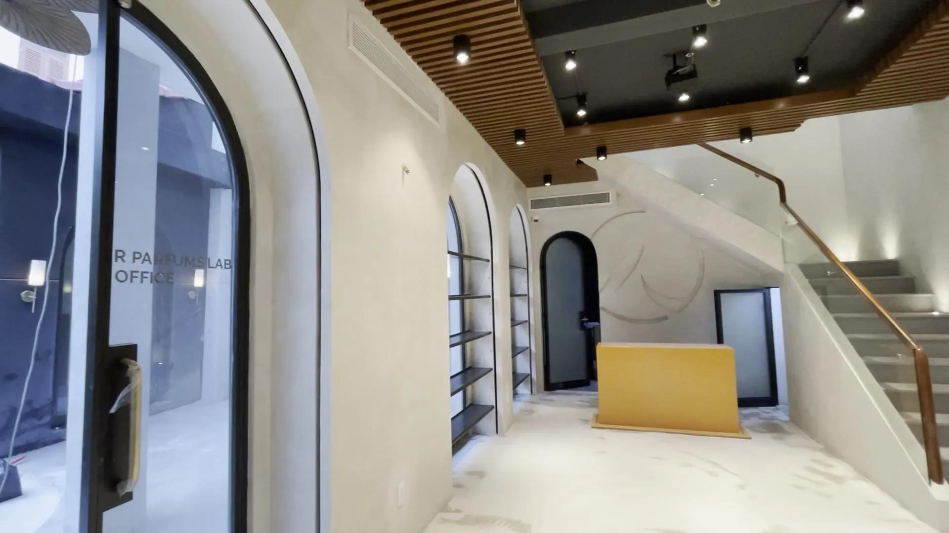 The finished hall, still empty: arched glass doors, arched shelves set into the wall, a slatted wooden ceiling with spotlights, a stone staircase with a wooden handrail, a round relief on the back wall