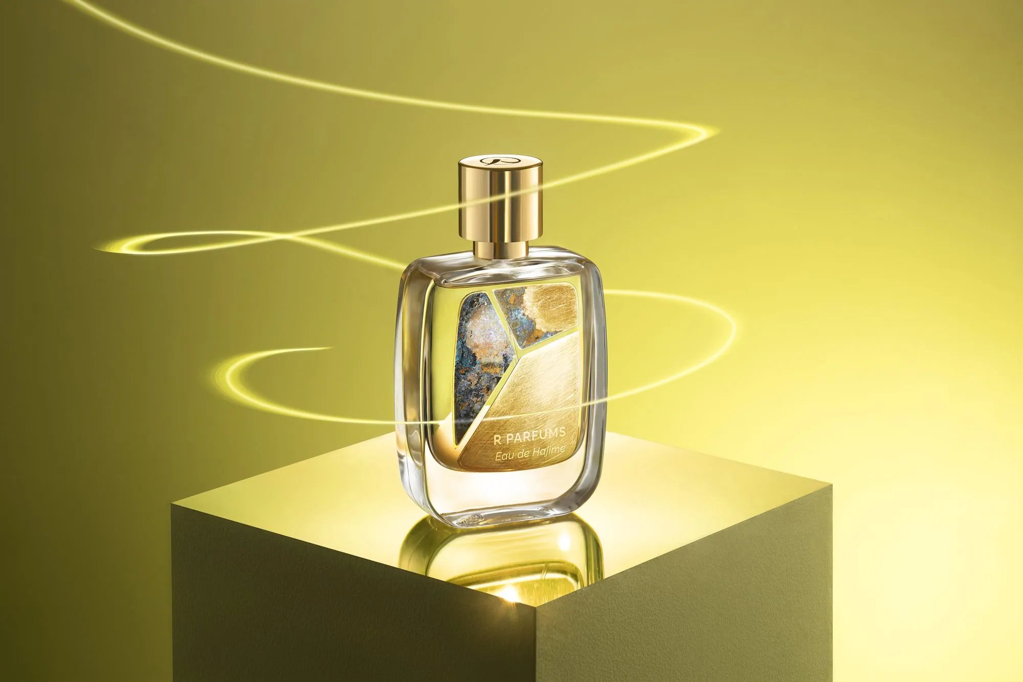 Eau de Hajime ในขวด Patina บนแท่นเรืองแสง มีริบบิ้นแสงวนรอบ บนพื้นหลังสีเหลืองมะนาว