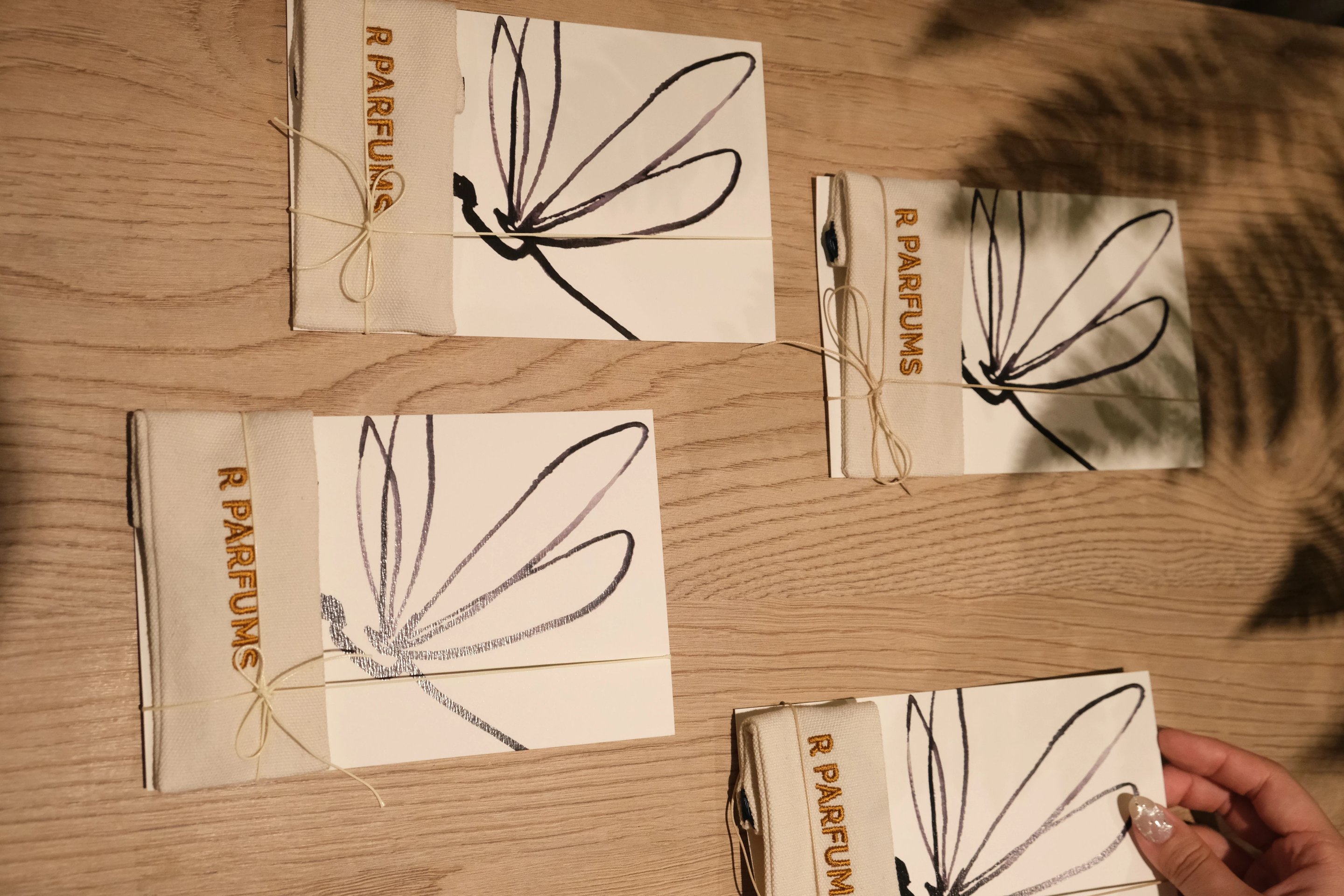 먹으로 잠자리를 그린 카드 네 장, 장마다 R PARFUMS 자수 천 주머니. 위에서 내려다본 모습